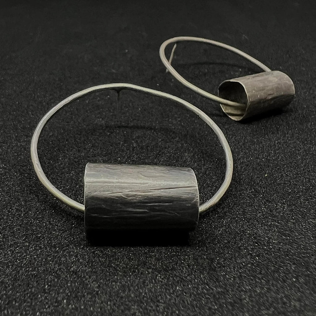 Pair of oxidized sterling silver Log Hoop Earrings on a dark surface